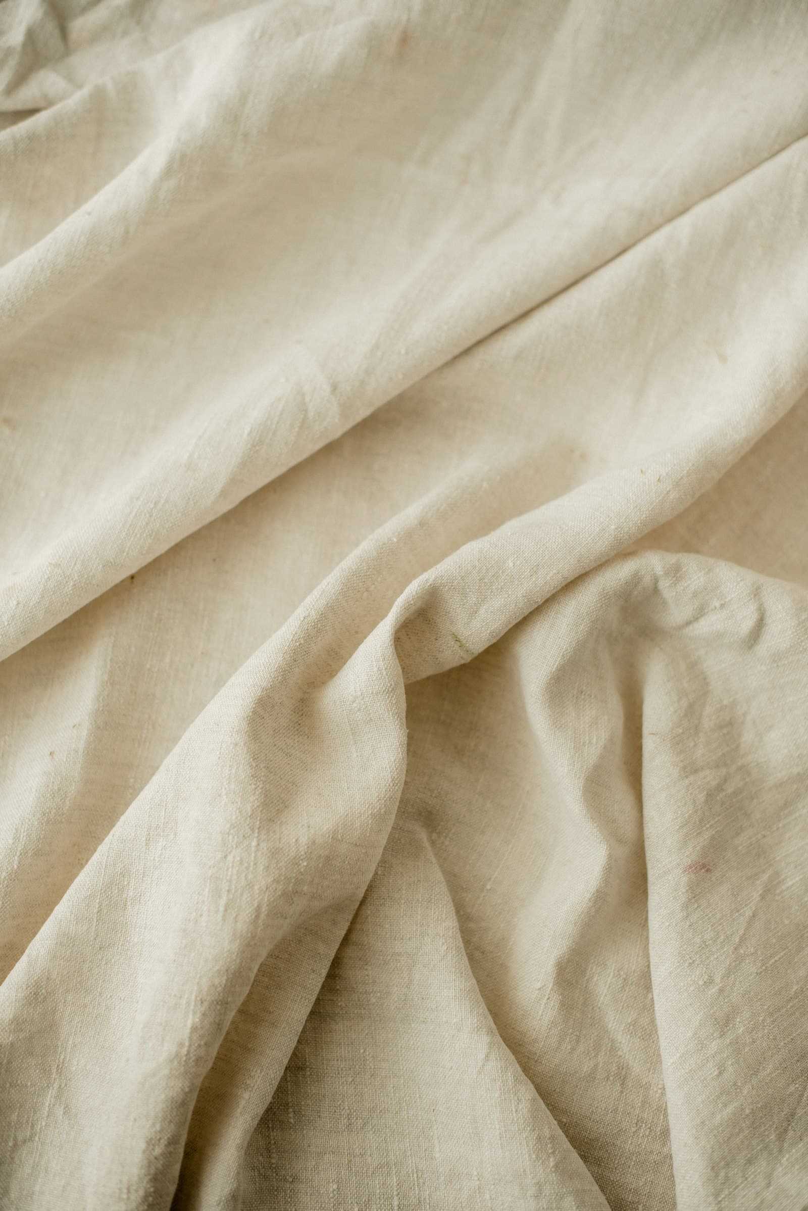 Close-up of crumpled natural oatmeal linen in loose soft folds showing its slub texture